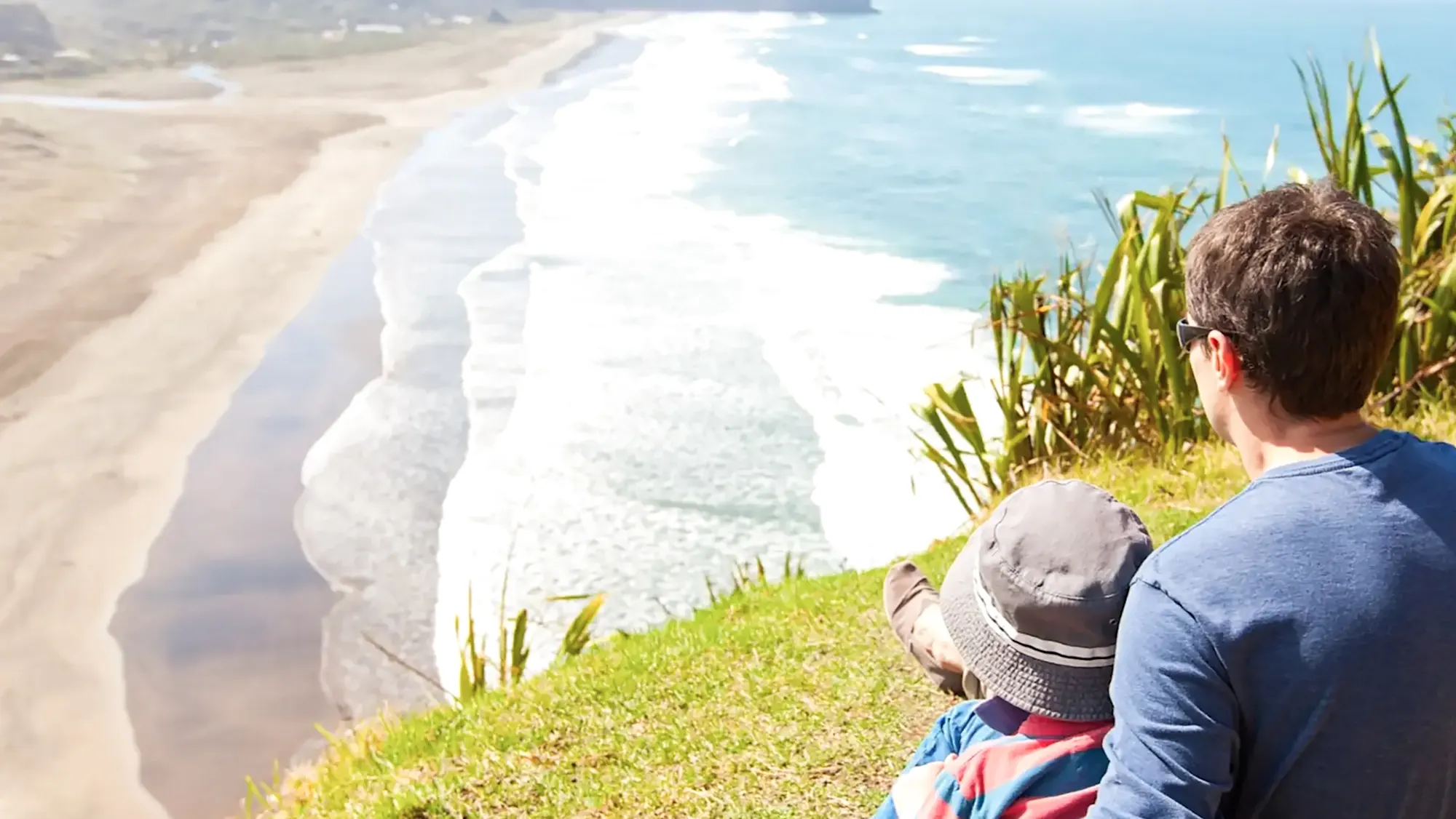 Neuseeland, Familienreise Vater und Sohn beobachten einen Strand in Neuseeland.
