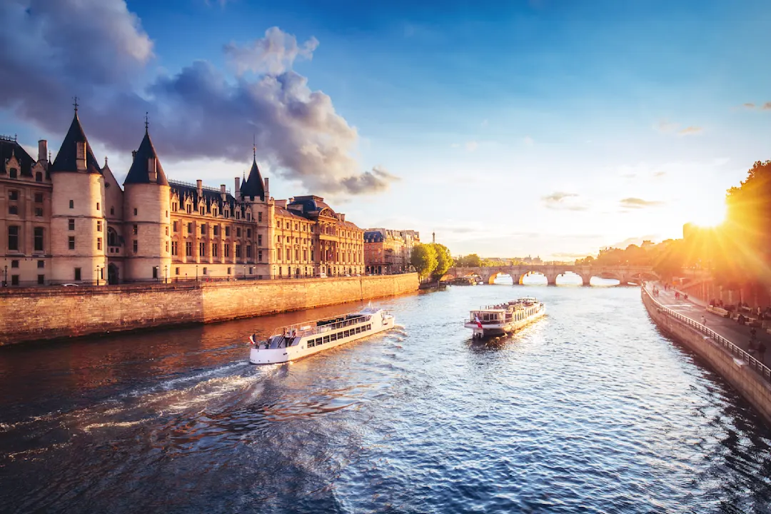 Europe, France, Paris, a view of the River Seine at sunset with boats cruising towards a bridge.