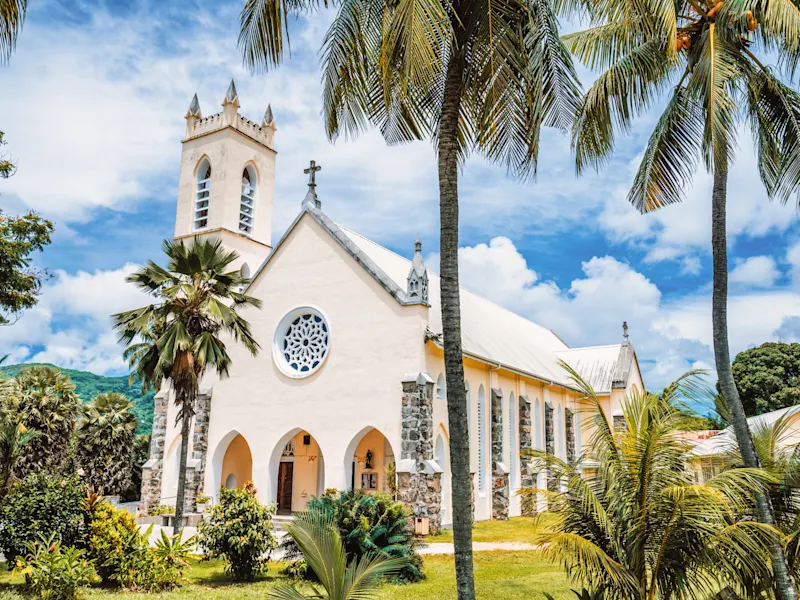 Victoria, Mahé, Seychellen Weiße Kirche mit Palmen und tropischer Umgebung unter blauem Himmel. Victoria, Mahé, Seychellen.