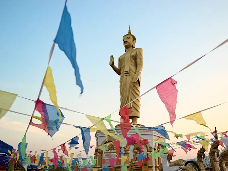 Laos, Vientiane, Buddha-Statue Große goldene Buddha-Statue mit Gebetsfahnen. Vientiane, Laos.