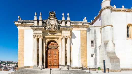 Blick auf den Eingang der Joanina Bibliothek in Coimbra mit weißer Fassade und kunstvoller Verzierung