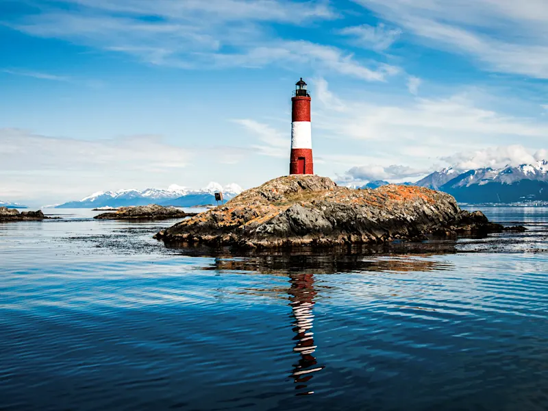 Argentinien, Tierra del Fuego, Ushuaia Roter Leuchtturm auf Felsen mit Bergen im Hintergrund. Ushuaia, Tierra del Fuego, Argentinien.