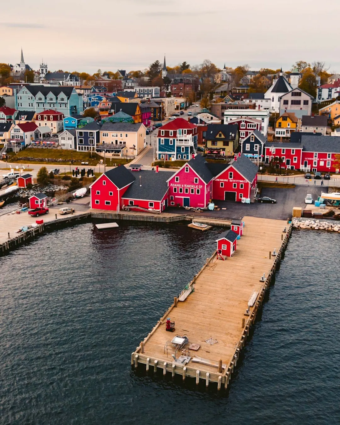 Luftaufnahme des Piers in Lunenburg, Kanada, mit lebendigen Gebäuden an der Uferpromenade und sichtbarem Wald im Hintergrund.