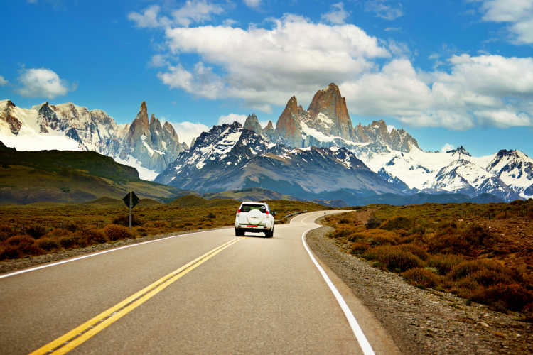 Geländewagen auf einer Straße on Patagonien mit Bergen im Hintergrund bei einem Roadtrip aufgenommen