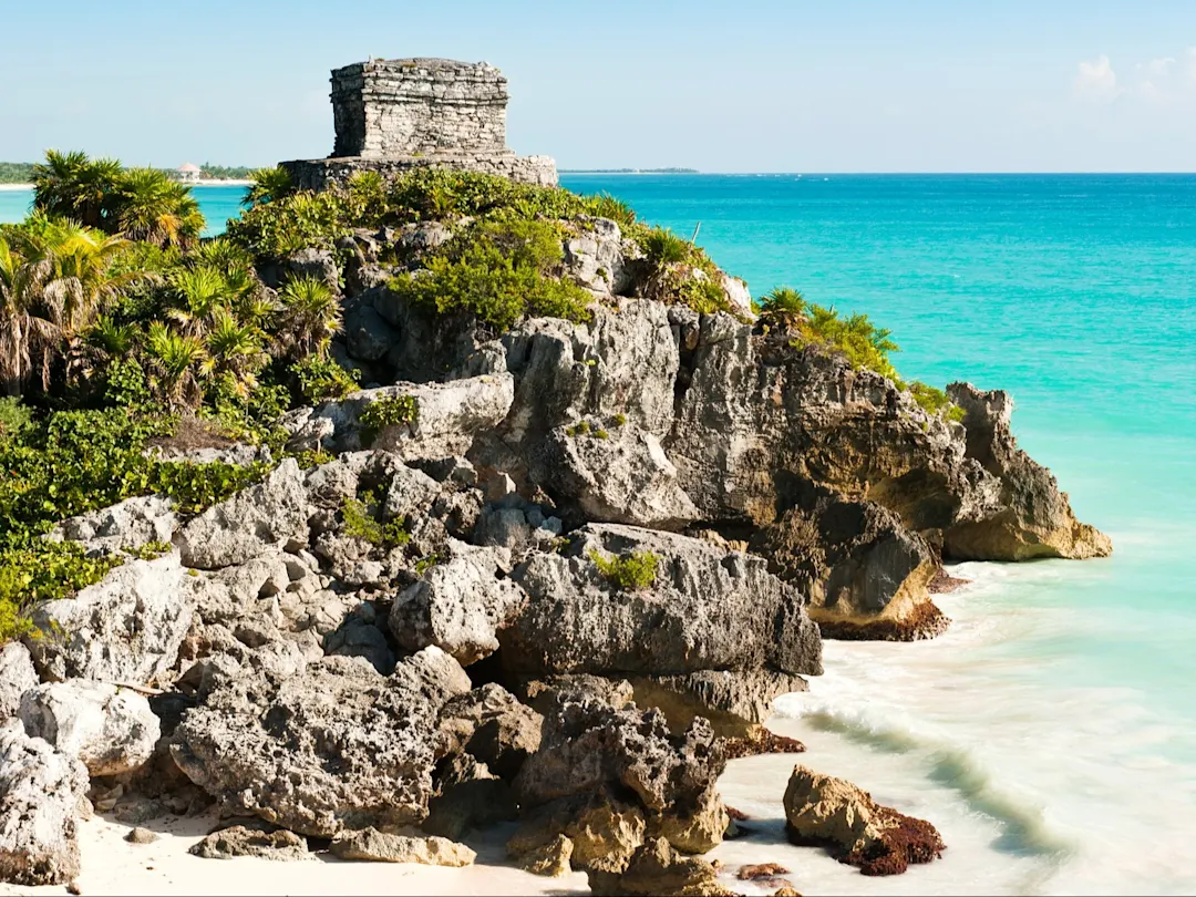 Ruinen der alten Maya-Stadt Tulum in Mexiko, aufgenommen an einem warmen Sommertag mit klarem blauen Himmel und türkisfarbenem Karibikmeer.