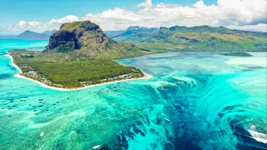 Vue aérienne du mont Le Morne entouré d'eau bleu turquoise, à l'île Maurice.
