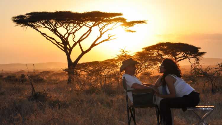 Ein Pärchen sitzt beim Sonnenuntergang, Tansania. 