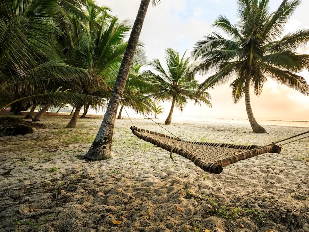 Kenia, Diani Beach Hängematte zwischen Palmen an einem Sandstrand bei Sonnenaufgang. Diani Beach, Kenia.