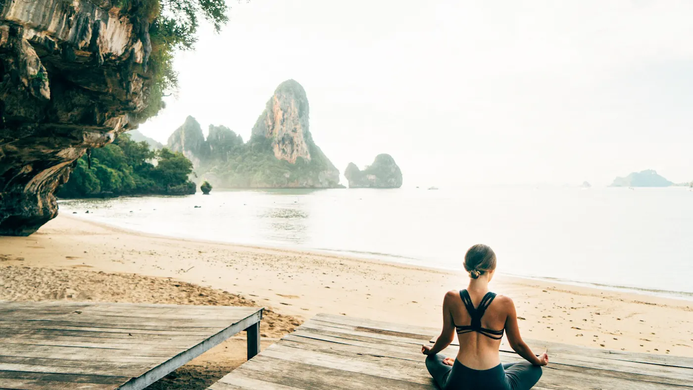 Thailand, Krabi, Kalksteinfelsen, Yoga Yoga am Strand mit Blick auf die Kalksteinfelsen, Krabi, Thailand.