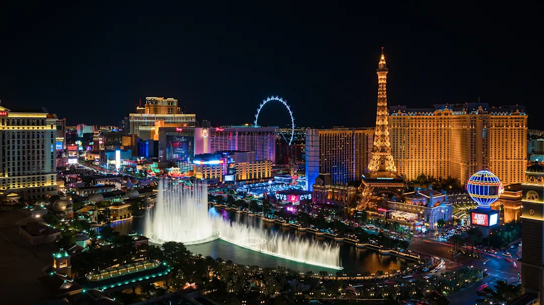 Nachtaufnahme des beleuchteten Las Vegas Strip mit Springbrunnen und Wahrzeichen. Nevada, USA.