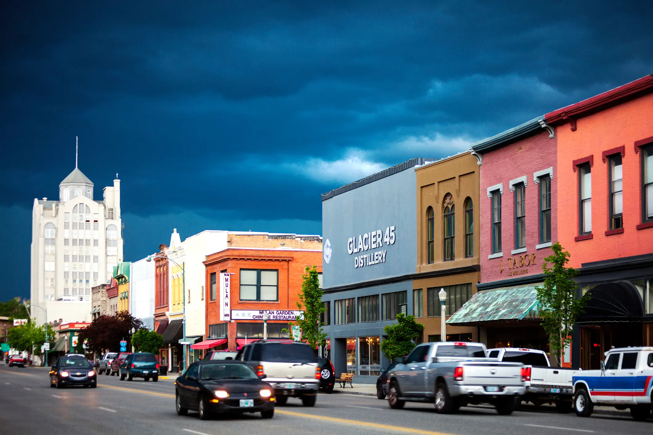 Belebte Innenstadt mit bunten Gebäuden und dunklen Gewitterwolken am Himmel, Baker City, Oregon, USA.