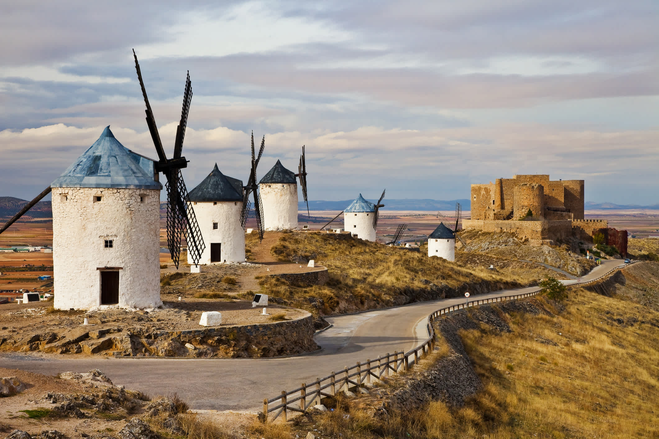 Eine Straße zwischen den Consuegra Windmühlen, Castilla La Mancha, Spanien. 

