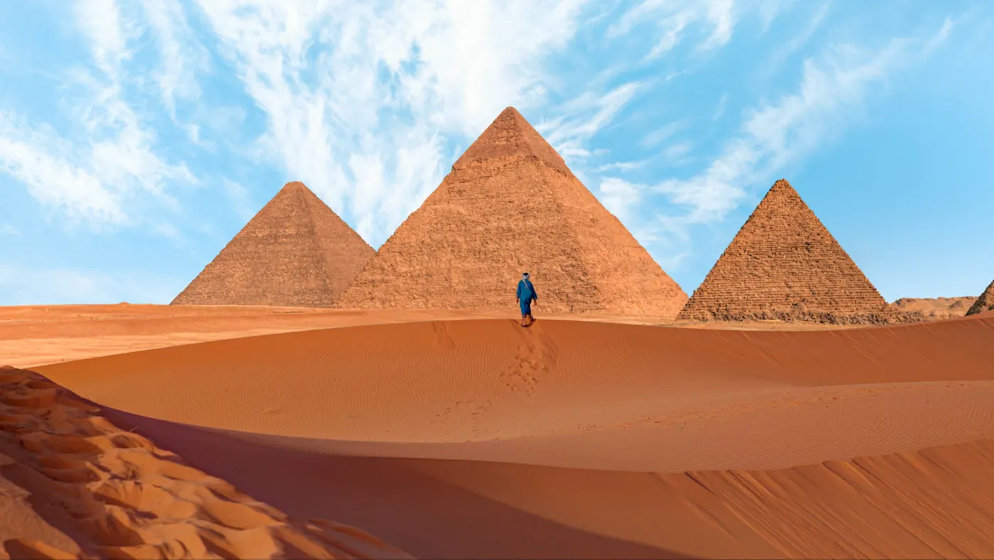 Gizeh, Kairo, Ägypten, Eine kleine menschliche Figur ist am Boden vor den Pyramiden zu sehen. Gizeh, Kairo, Ägypten,