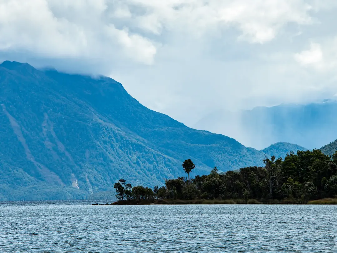 Neblige Berge über einem See, West Coast, Südinsel, Neuseeland.
