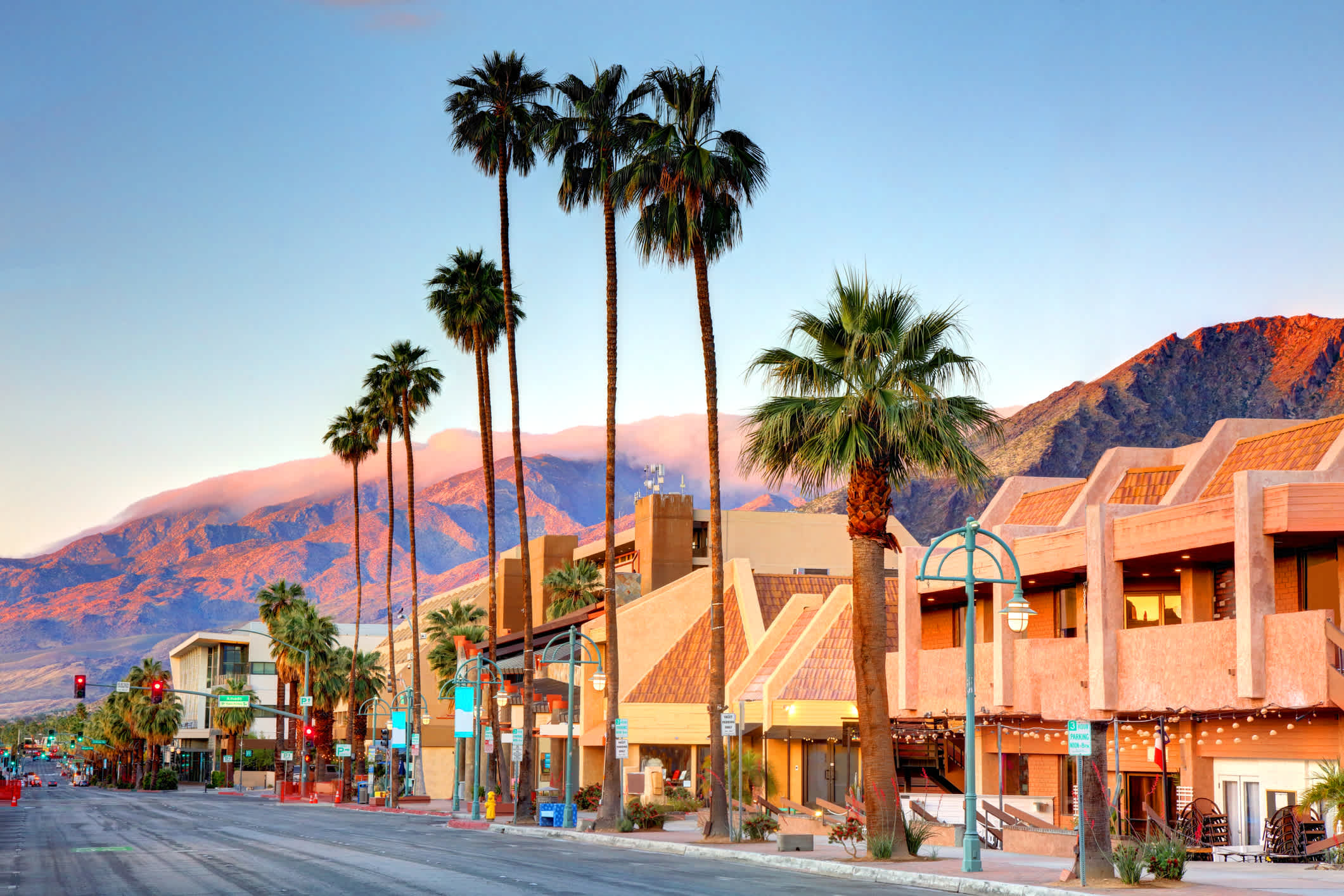 Route centrale dans le centre de Palm Springs bordé de palmiers avec des montagnes en arrière-plan.