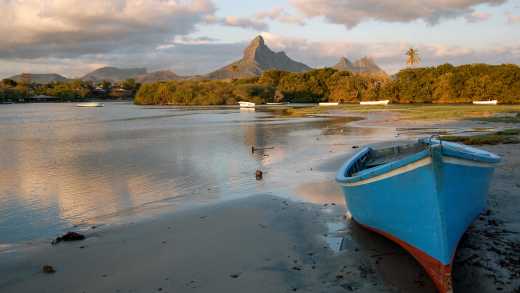 Bateau bleu échoué sur le sable au bord de la plage de Tamarin au coucher du soleil, île Maurice