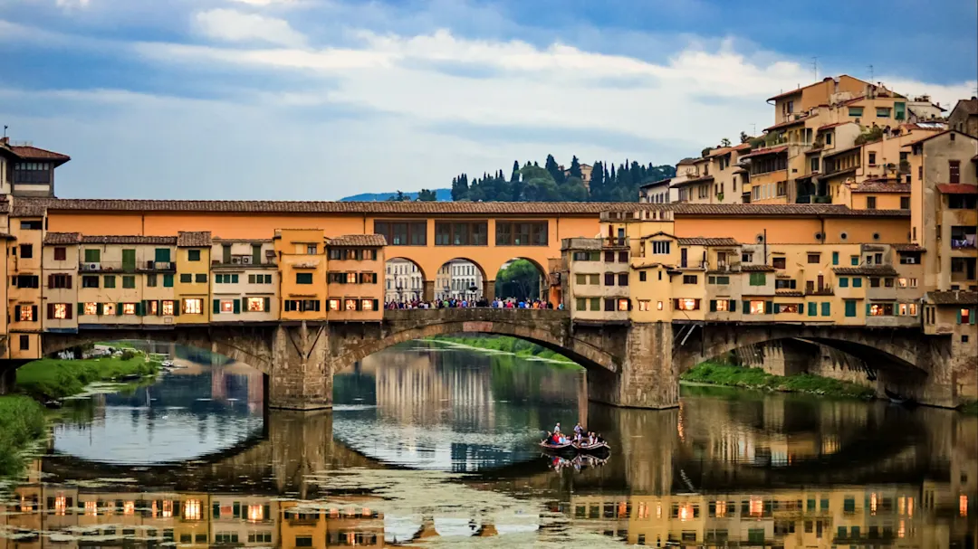 Der Ponte Vecchio in Florenz, Italien, mit einer Bootsfahrt im Fluss Arno.
