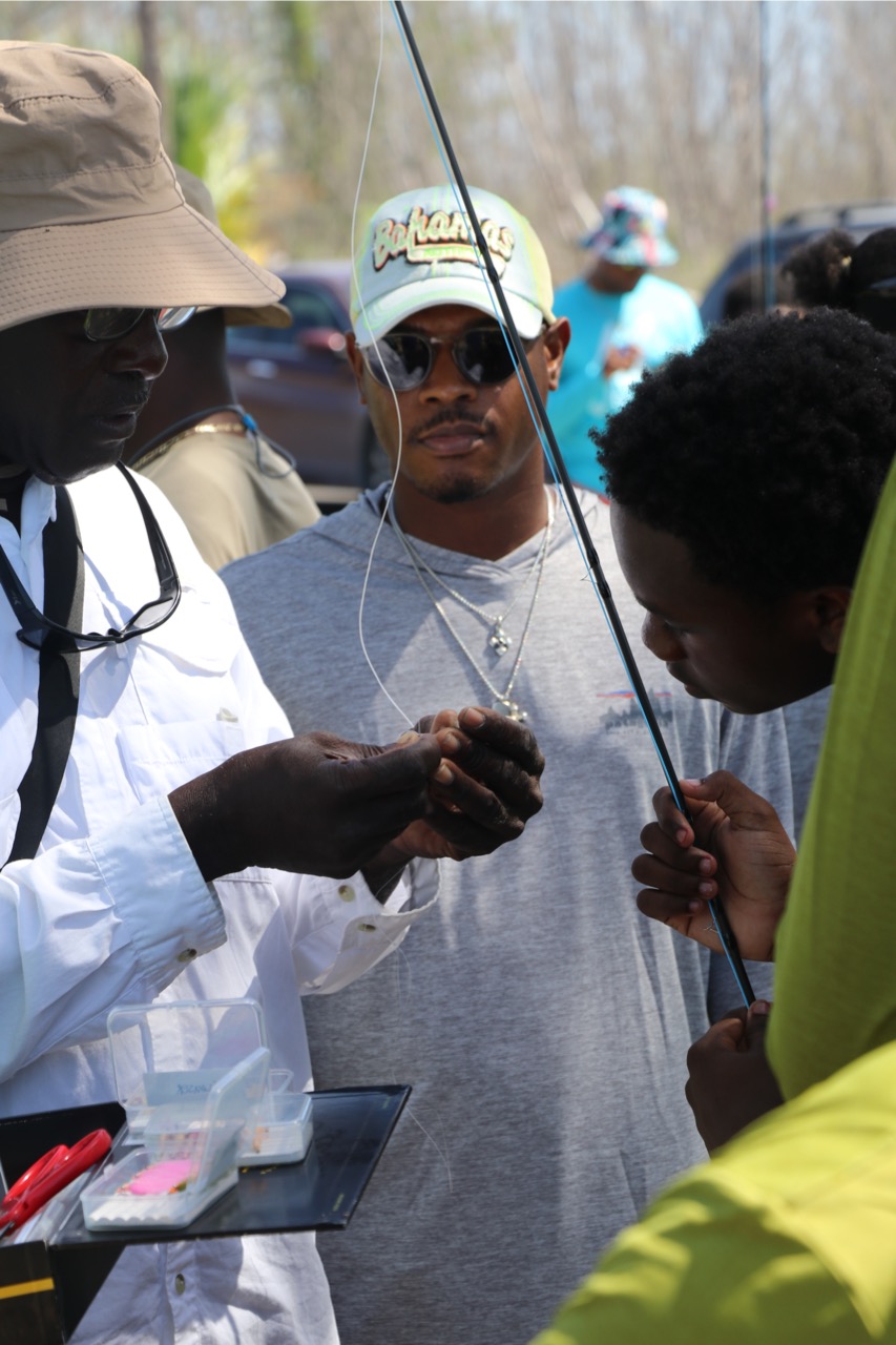 Young man watching the community fly fishing guide tie a fly on.