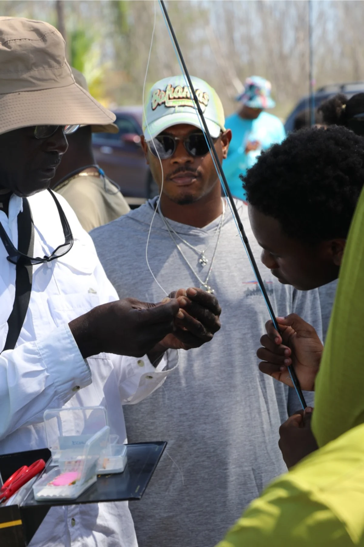 Young man watching the community fly fishing guide tie a fly on.