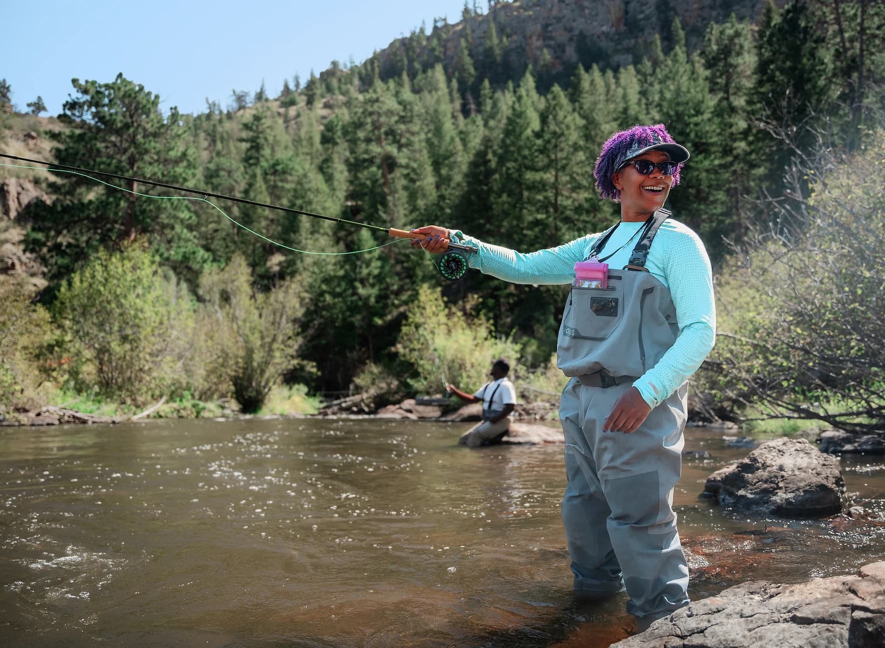 Woman fly fishing in the river, smiling