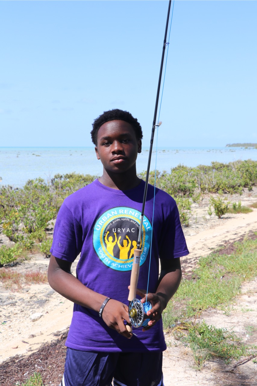 Young man holding a fly fishing rod on the beach