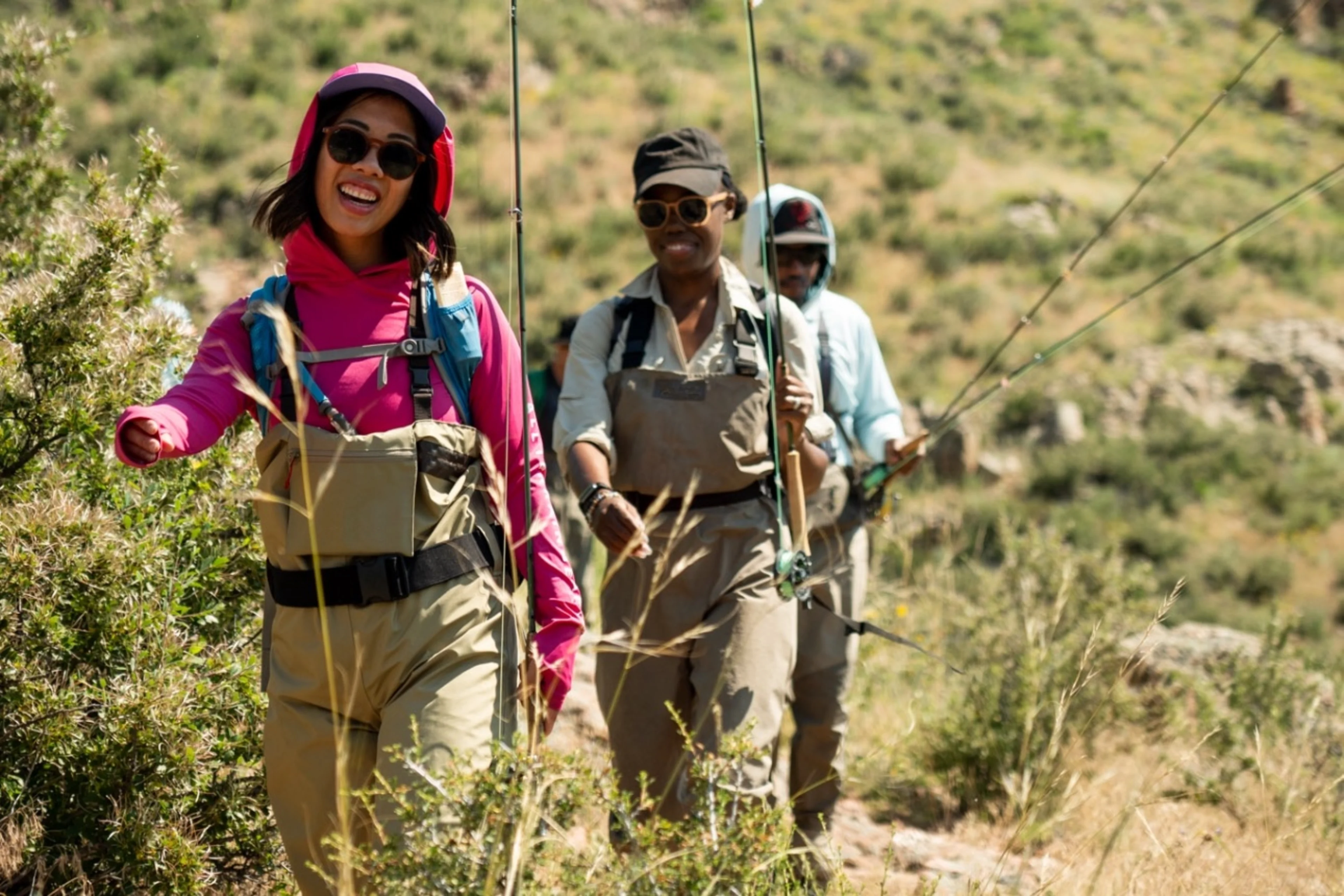 Three anglers hiking on a trail in their fly fishing gear