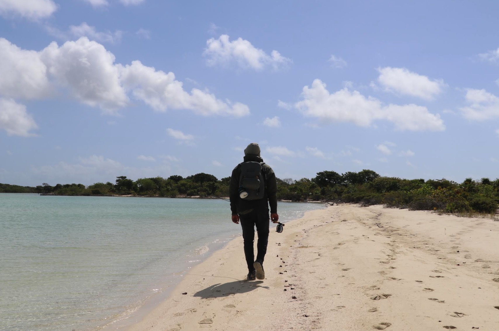 Community Fly Fishing walking along the beach with a fishing rod