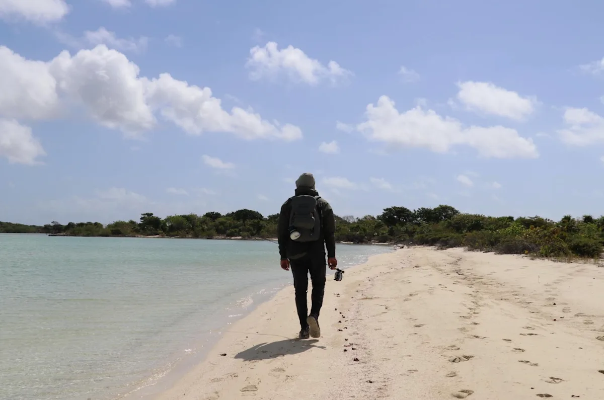 Community Fly Fishing walking along the beach with a fishing rod