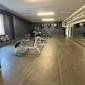 Träningslokaler med grå väggar, gummigolv, träningsutrustning, hantlar, speglar och gymbollar på väggen.