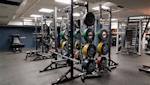 Modernt gym med power racks och färgglada viktskivor i grönt, gult, rött och blått på grått golv.