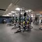 Modernt gym med power racks och färgglada viktskivor i grönt, gult, rött och blått på grått golv.