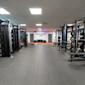 Modernt gym med styrketräningsutrustning, bänkpressar och vikter. Texten "PERFORMANCE ZONE" på väggen.