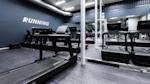 Moderne treningsstudio med løpebånd og svarte treningsapparater. Blå vegg med teksten RUNNING i hvitt.