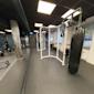 Modernt gym med vit träningsram, svart boxningssäck och träningsutrustning under takbelysning med mörkt tak.