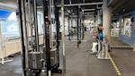 Modernt gym med svarta träningsapparater, mörkt tak och stora fönster. Träningsutrustning och vikter synliga.