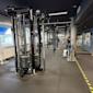 Modernt gym med svarta träningsapparater, mörkt tak och stora fönster. Träningsutrustning och vikter synliga.