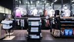 Moderne shop med treningsklær på stativer, Casall-produkter i forgrunnen og fargerike t-skjorter på veggen.