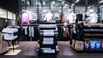 Moderne shop med treningsklær på stativer, Casall-produkter i forgrunnen og fargerike t-skjorter på veggen.