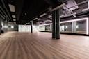 Moderne hotstudio med tregulv, svart tak, søyler og store speil med LED-belysning langs veggene.