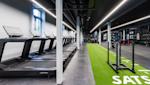 Moderne treningsstudio med tredemøller til venstre og grønn treningsmatte med hvite markeringer til høyre.