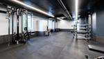 Moderne treningsstudio med svart tak, hvite vegger, grått gulv og treningsutstyr som kabelmaskin og vektstativ.