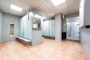 Moderne garderobe med lyseblå skap, benker og beige fliser på gulvet i et lyst rom med grå vegger.