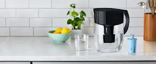 Black Brita pitcher on kitchen counter, next to Elite filter and glass of water.