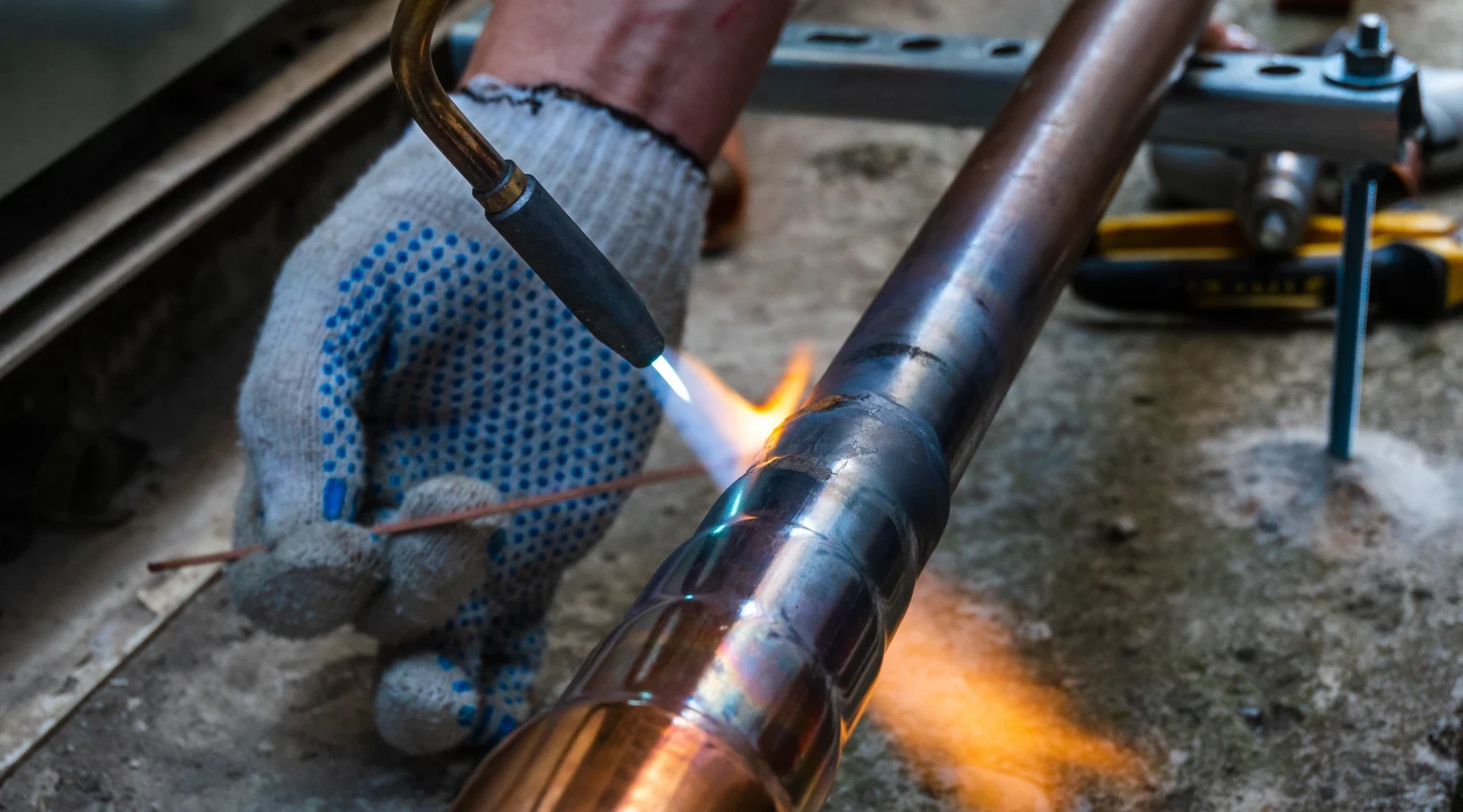 Construction worker welding copper pipe.