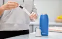 Person in kitchen replacing Brita water bottle filter.