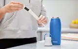 Person in kitchen replacing Brita water bottle filter.
