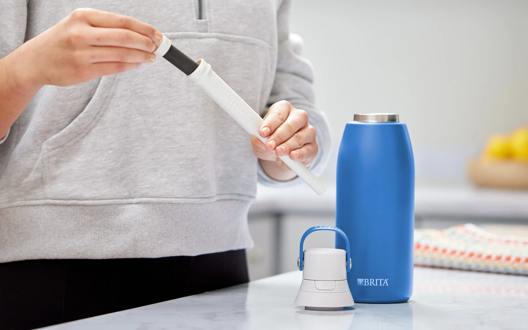 Person in kitchen replacing Brita water bottle filter.