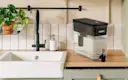 Black Ultramax Water Dispenser with Original Filter on kitchen counter, next to sink.