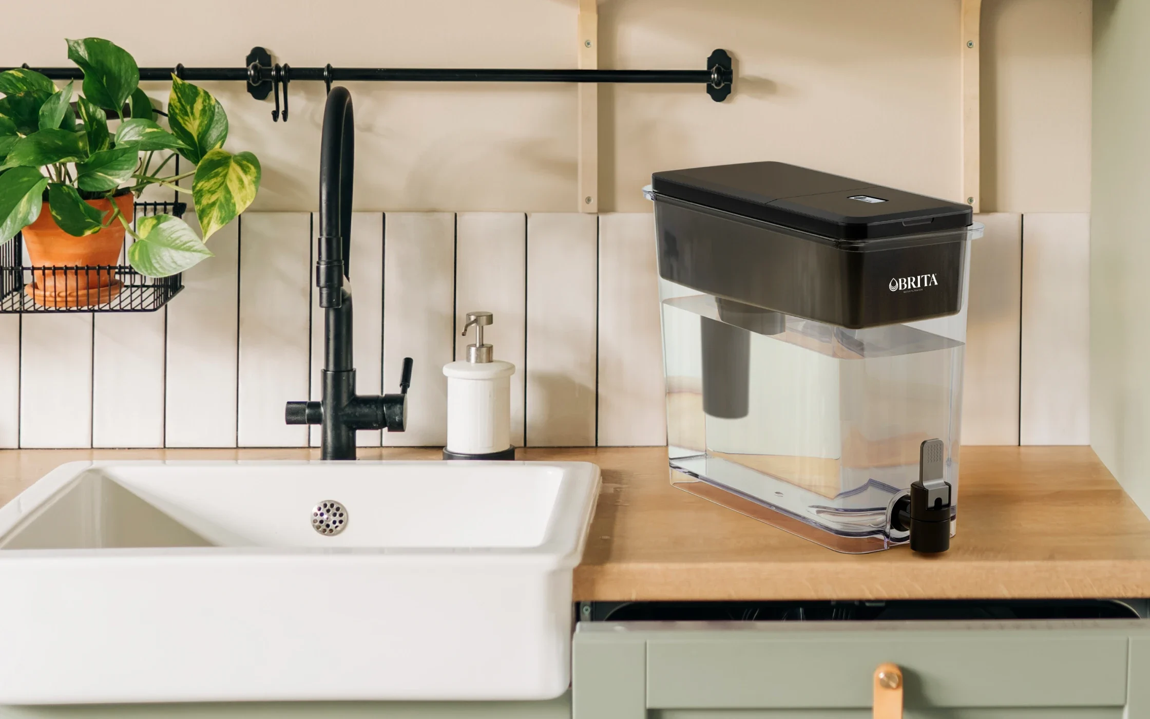 Black Ultramax Water Dispenser with Original Filter on kitchen counter, next to sink.