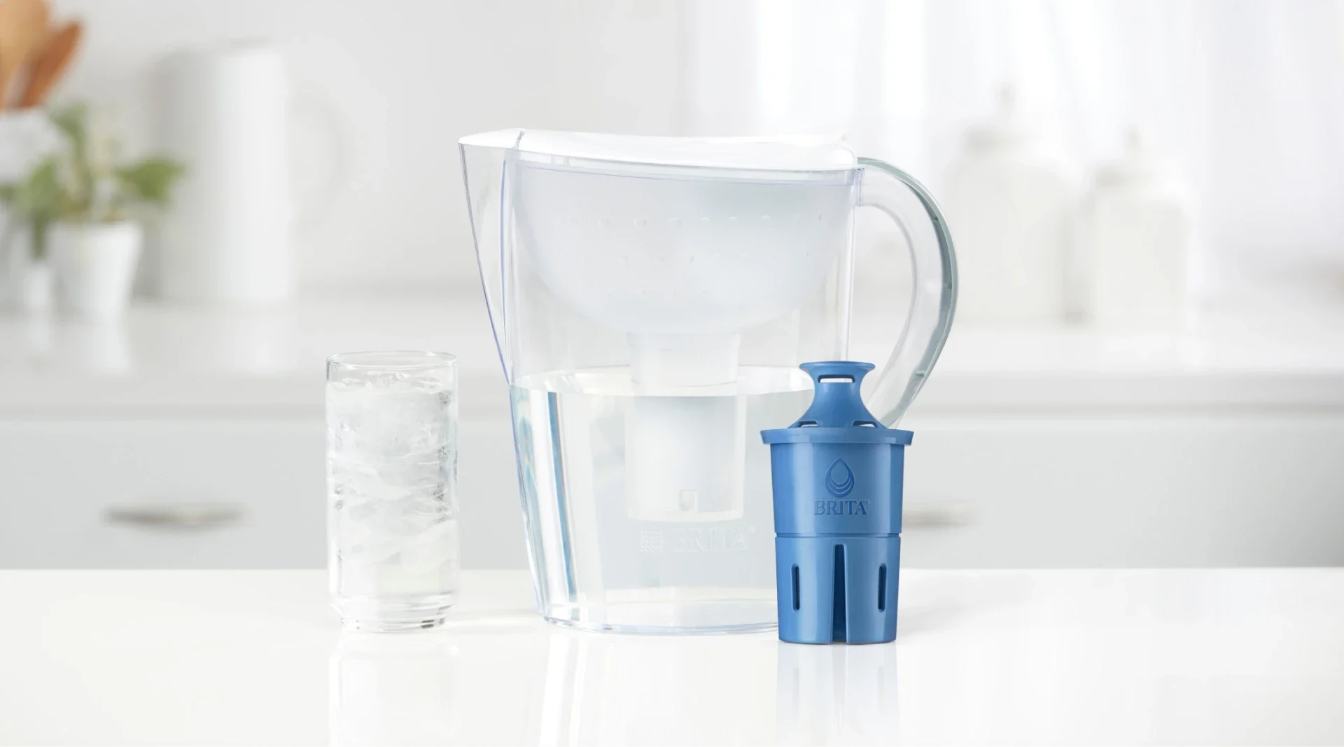 White Brita pitcher on kitchen counter, next to Brita Elite filter and water glass filled with ice and water.